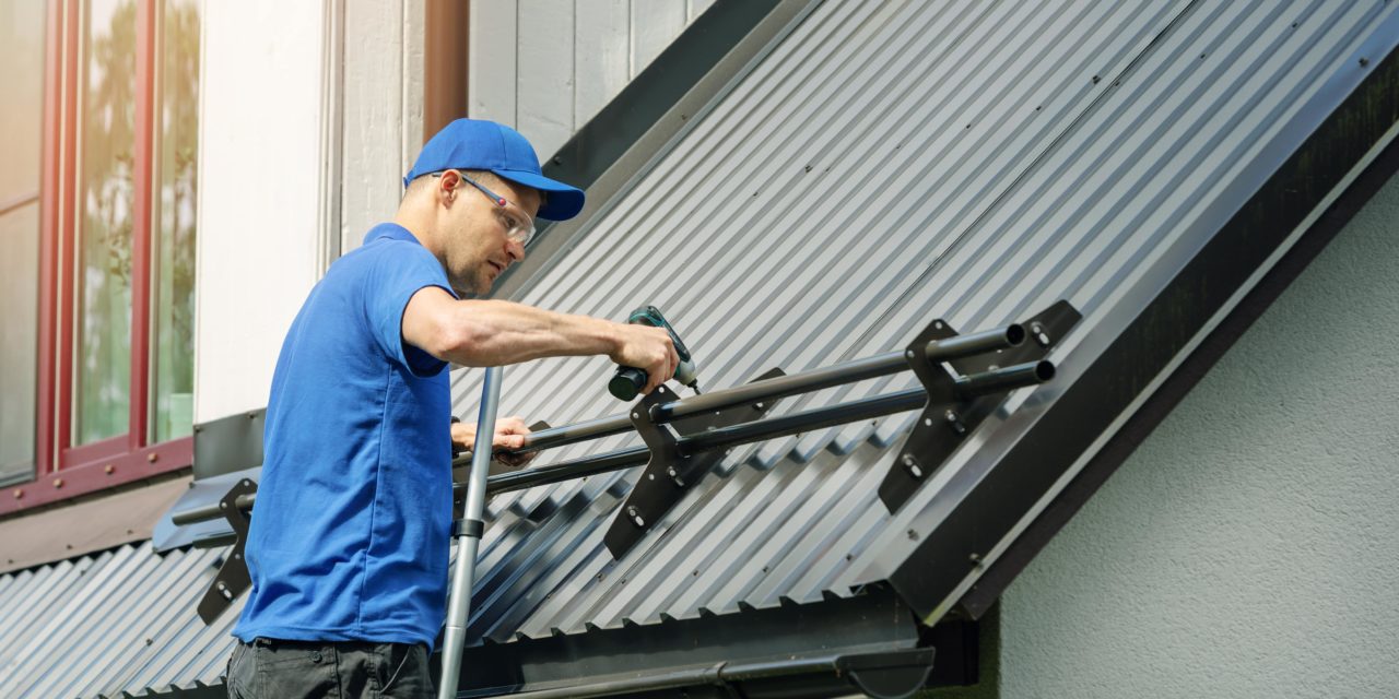 https://www.rpsmetalroofing.com/wp-content/uploads/2021/10/roofer-installing-snow-guards-metal-roof-1280x640.jpg